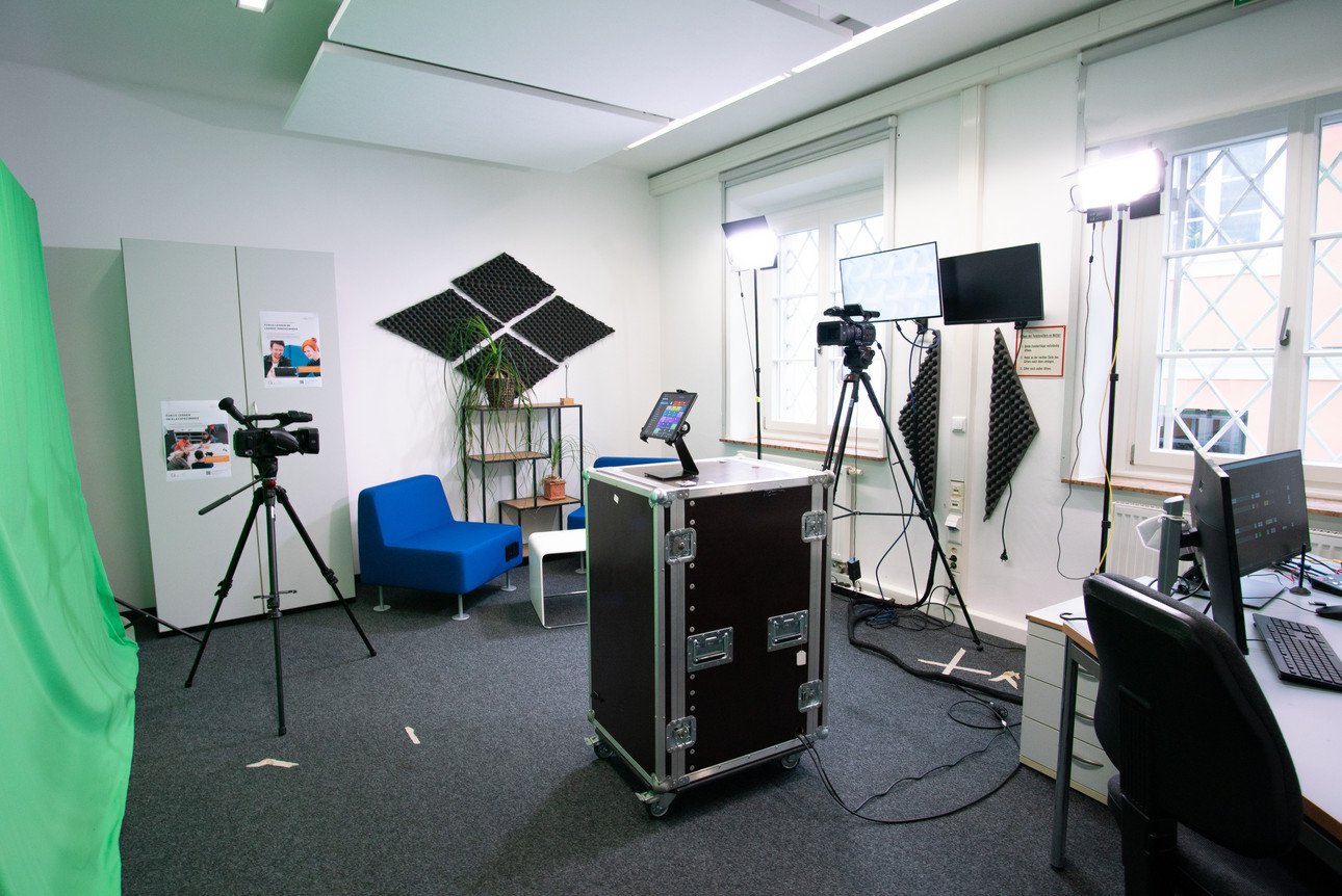Modernes Studio f&uuml;r Lehr- und Lernmittel-Erstellung mit professioneller Ausr&uuml;stung f&uuml;r Erkl&auml;rvideos, Podcasts und Interviews. Kleines, flexibles Setup f&uuml;r bis zu 4 Personen mit Greenscreen, Kamera auf Stativ, Beleuchtung und Arbeitsplatz. Ideal f&uuml;r Talking Head-Videos, Bewegungsabl&auml;ufe und Audioformate.