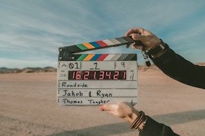 Hand h&auml;lt Filmklappe mit Countdown-Zeit in einer w&uuml;stenlandschaftlichen Umgebung f&uuml;r optimale Filmproduktion