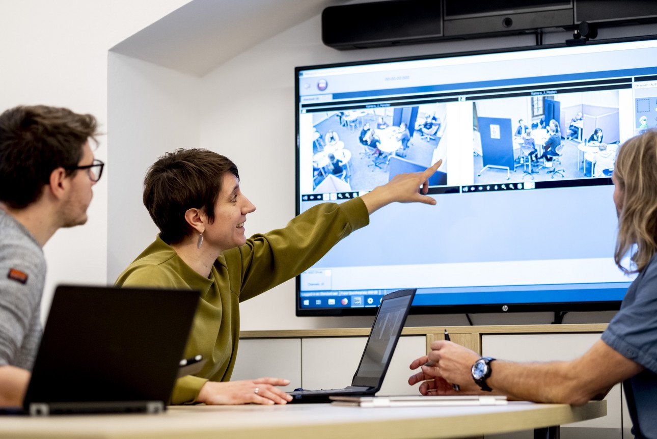 Lehrkraft bei einer Pr&auml;sentation vor einem interaktiven Whiteboard, Diskussion von Unterrichtsfilmaufnahmen in einem modernen Konferenzraum